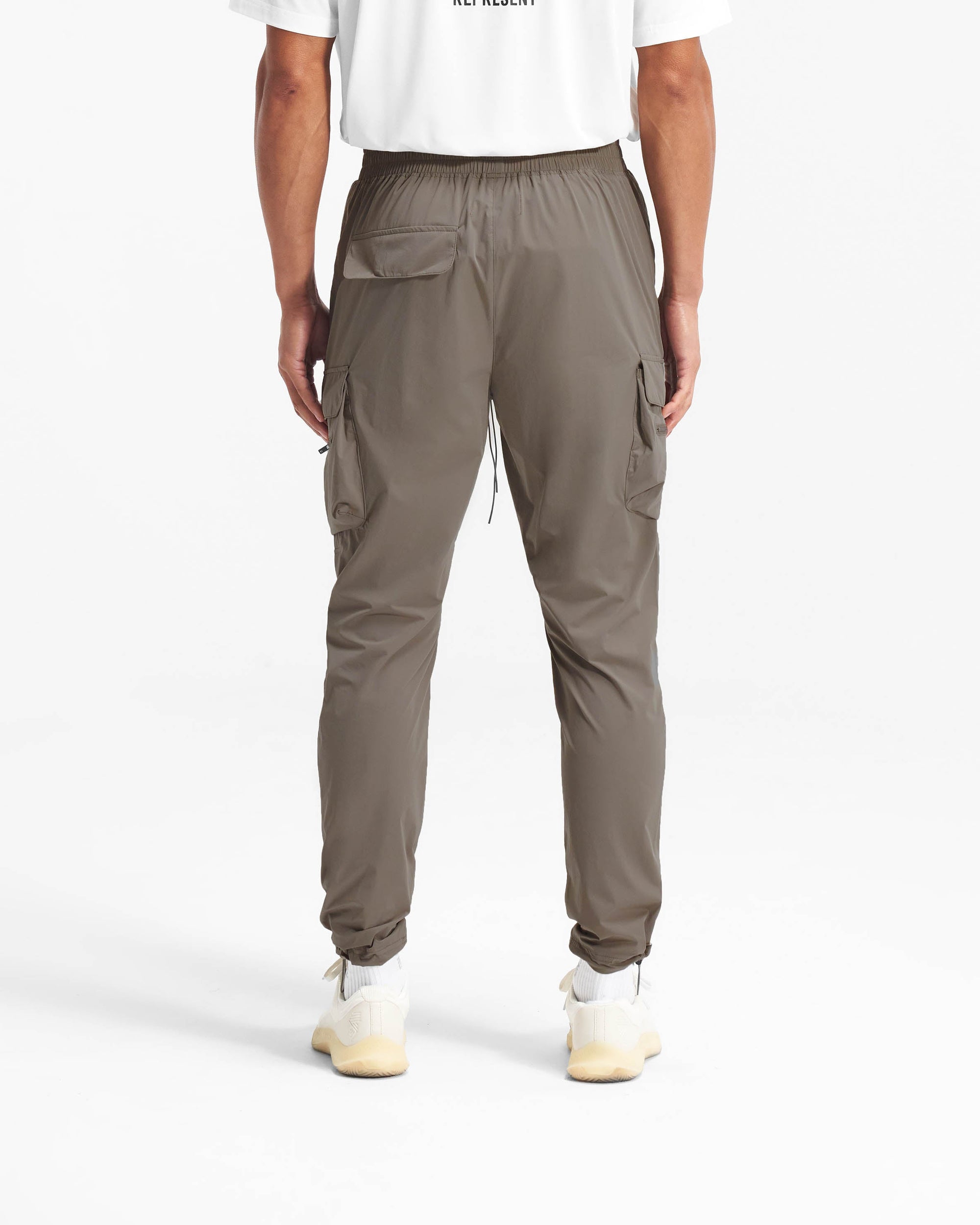 Man wearing olive cargo pants on a plain white background | 247 Pant in Olive | Cargo pants with spacious pockets and adjustable waistband | 247 Pants | Represent Clo